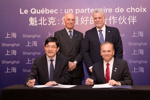 McGill’s Vice-Dean of Life Sciences, Philippe Gros (seated right), and Fudan University’s Wen Chen sign the agreement between the two universities as Jacques Daoust, Quebec’s Minister of Economy, Innovation and Exports (standing, left) and Quebec Premier Phillippe Couillard look on. / Photo: Patrick Alleyn