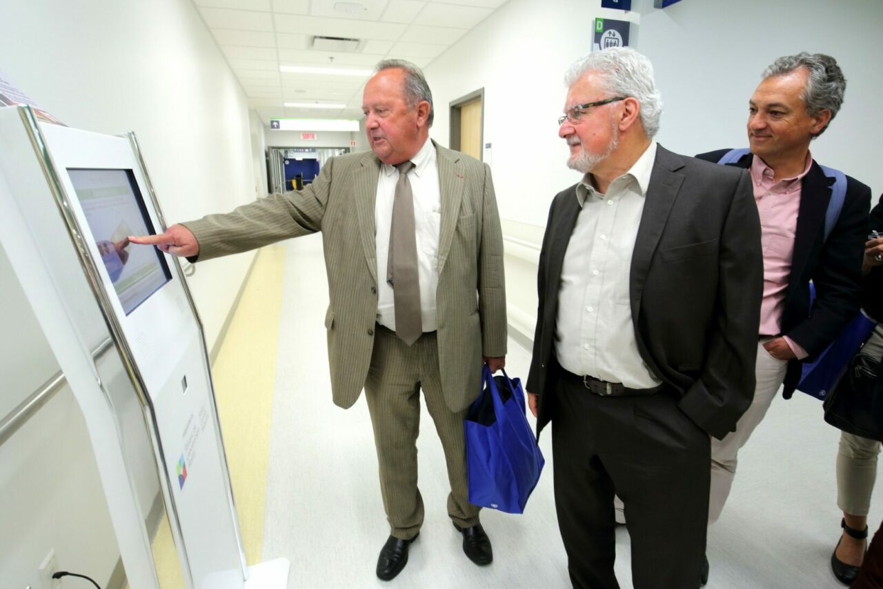 Jean Pierre DeWitte (left), director general of the CHU de Poitiers, tests out the new RCN self-check-in kiosks being piloted at the MUHC. / Photo: Owen Egan